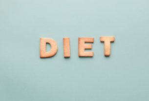 Alphabet cookies spelling 'diet' on a soft turquoise background, shot as a flat lay.