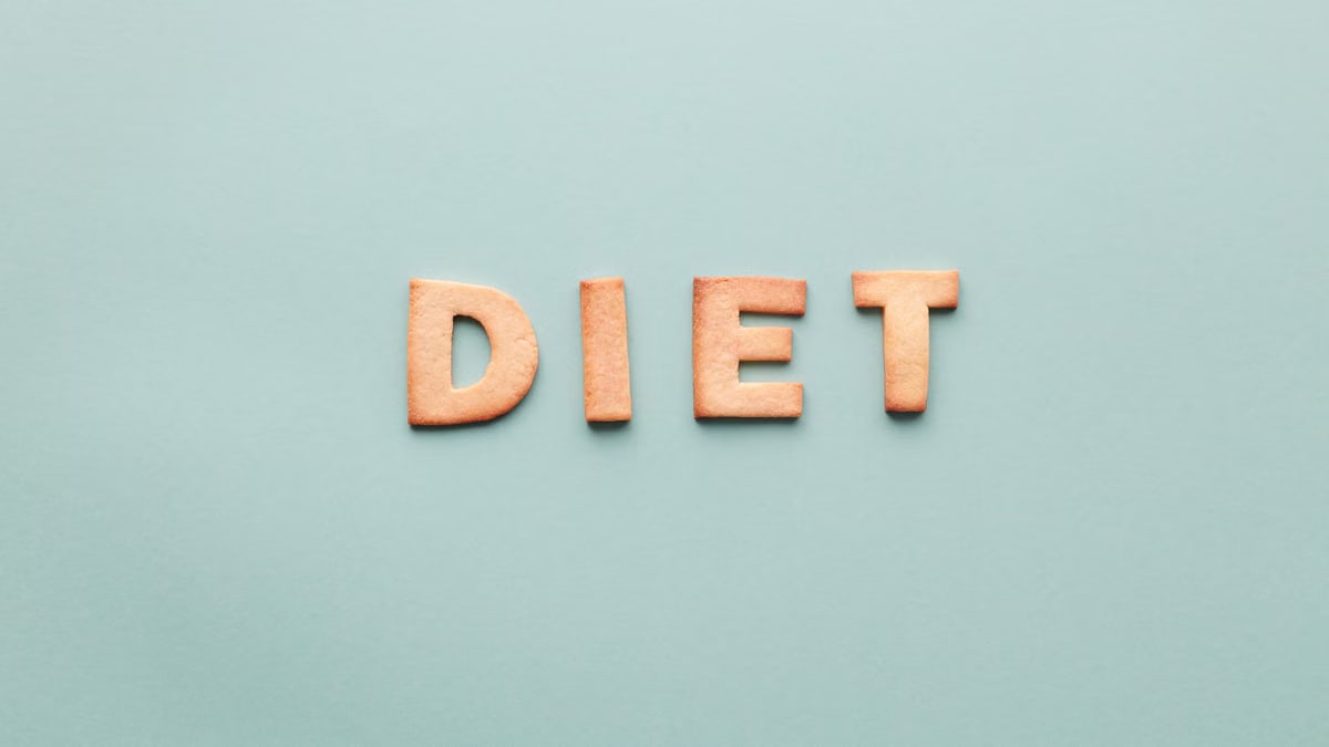 Alphabet cookies spelling 'diet' on a soft turquoise background, shot as a flat lay.